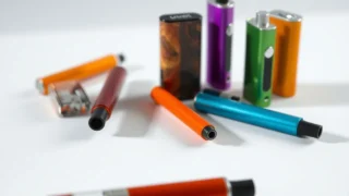 Non-smokers vaping: colourful e-cigarettes vape devices on white surface